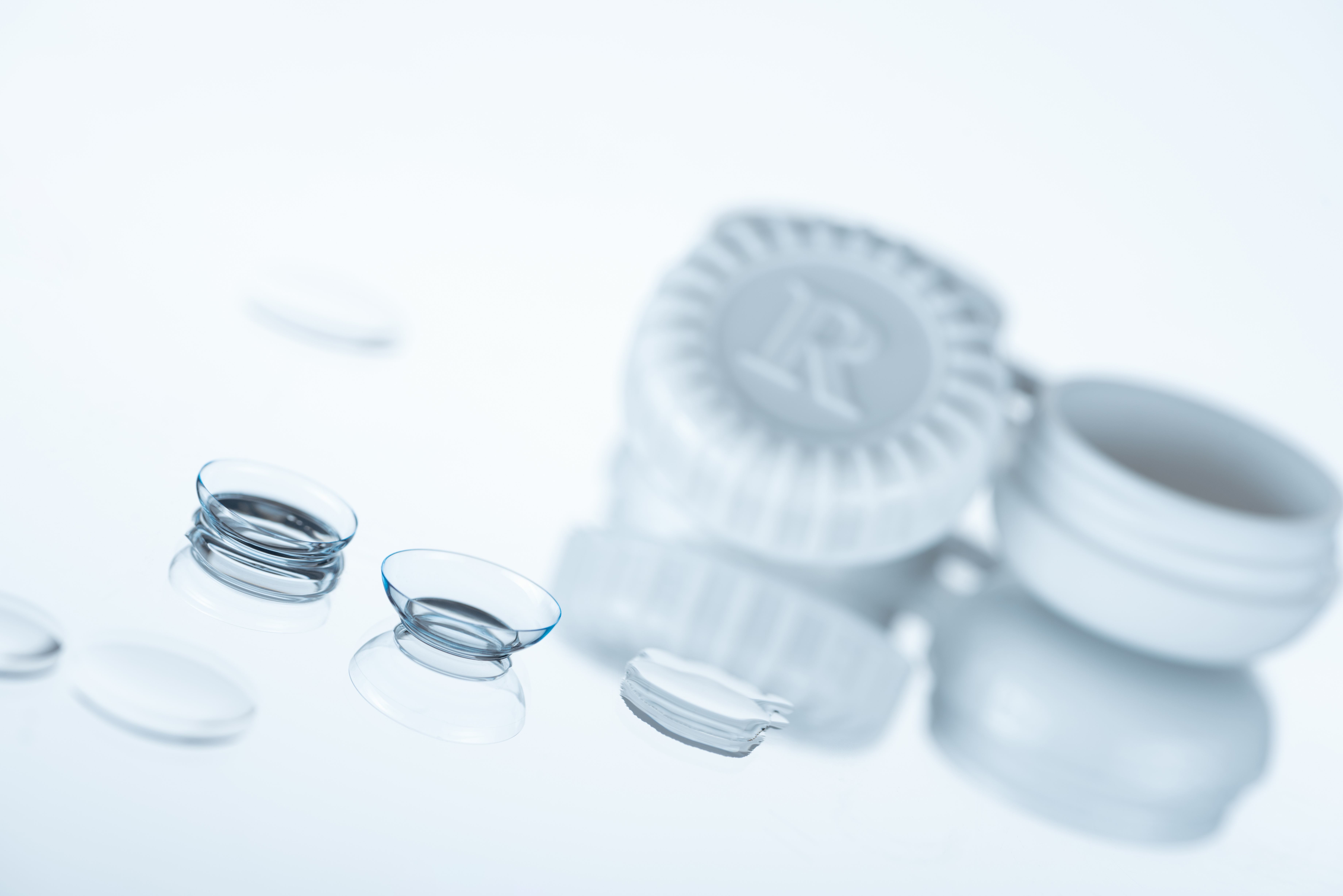 Selective focus of contact lenses and container on watery background frames