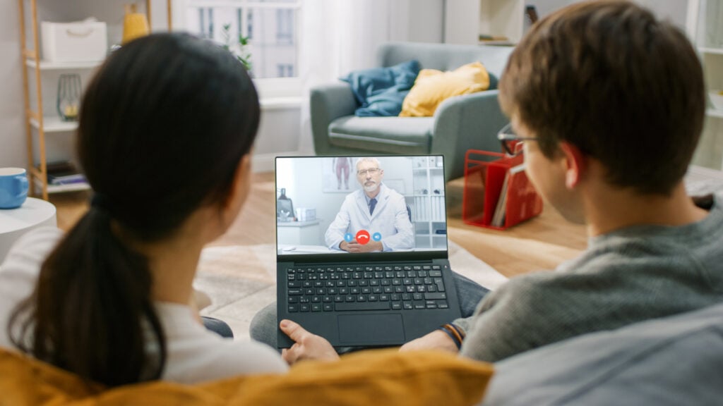Young Couple of a Girl and Man Sitting at Home doing online consultation with a doctor