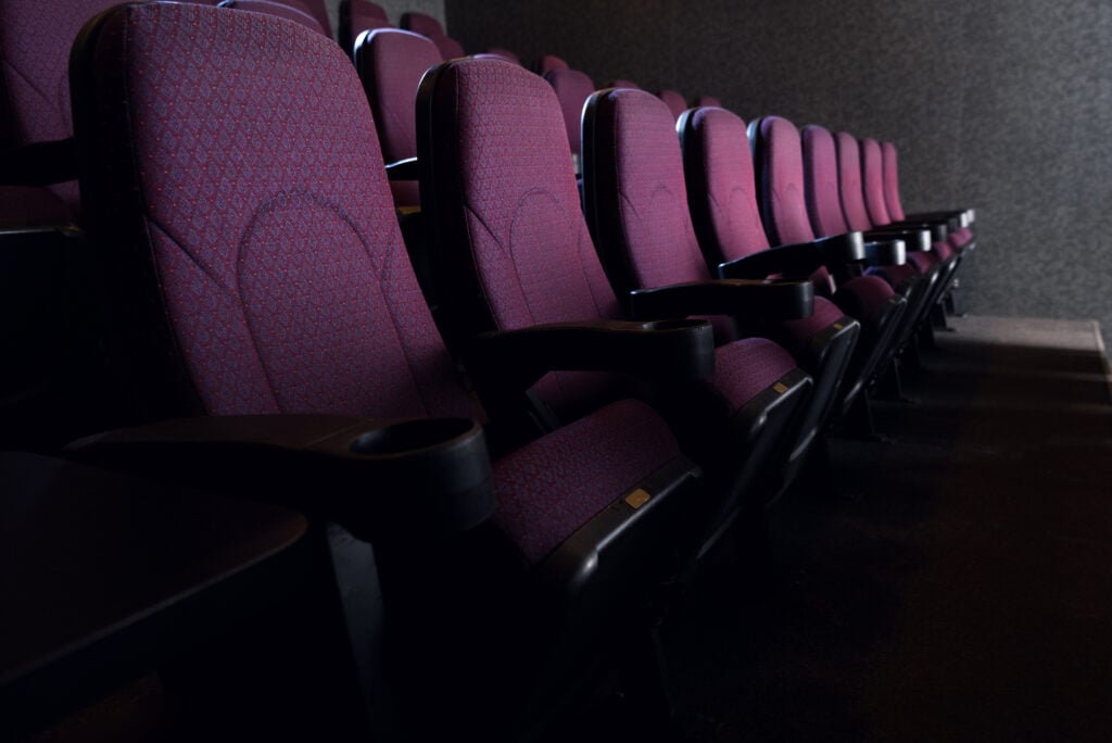 Rows of seats in a movie theater being shown through a dim light