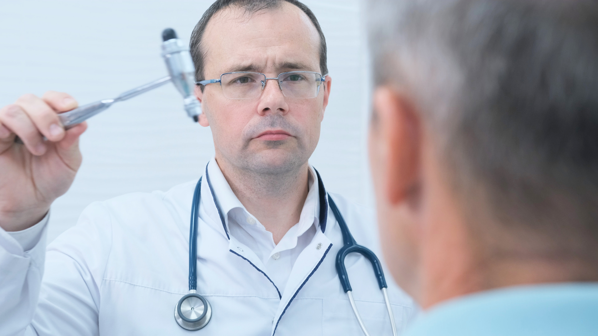 A neurologist examines the nervous system vision and reflexes of a male through a Nystagmus test