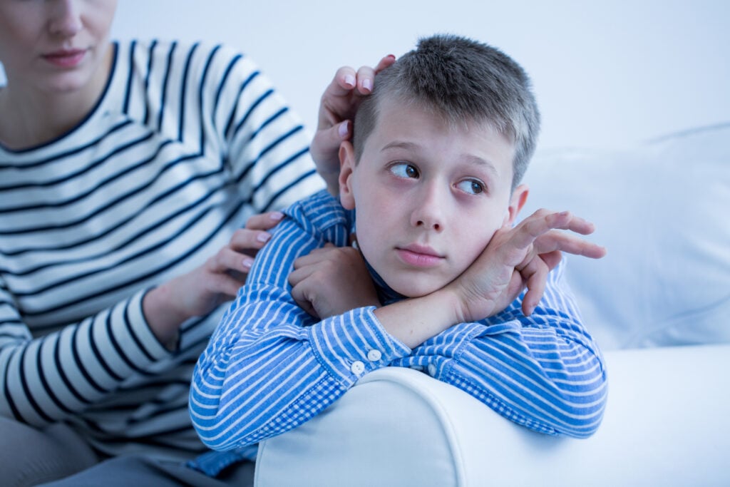 Autistic Child Lying on Sofa Looking Away from Mother Photo
