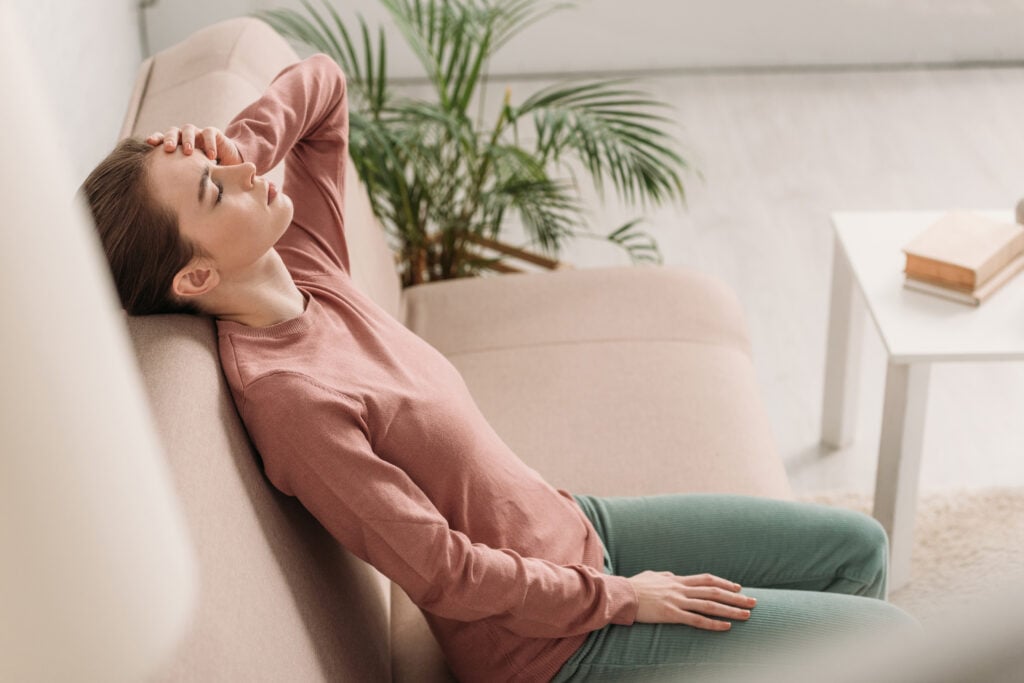 11 Home Remedies for a Black Eye 2 Selective focus of girl sitting on sofa with closed eyes and suffering from headache