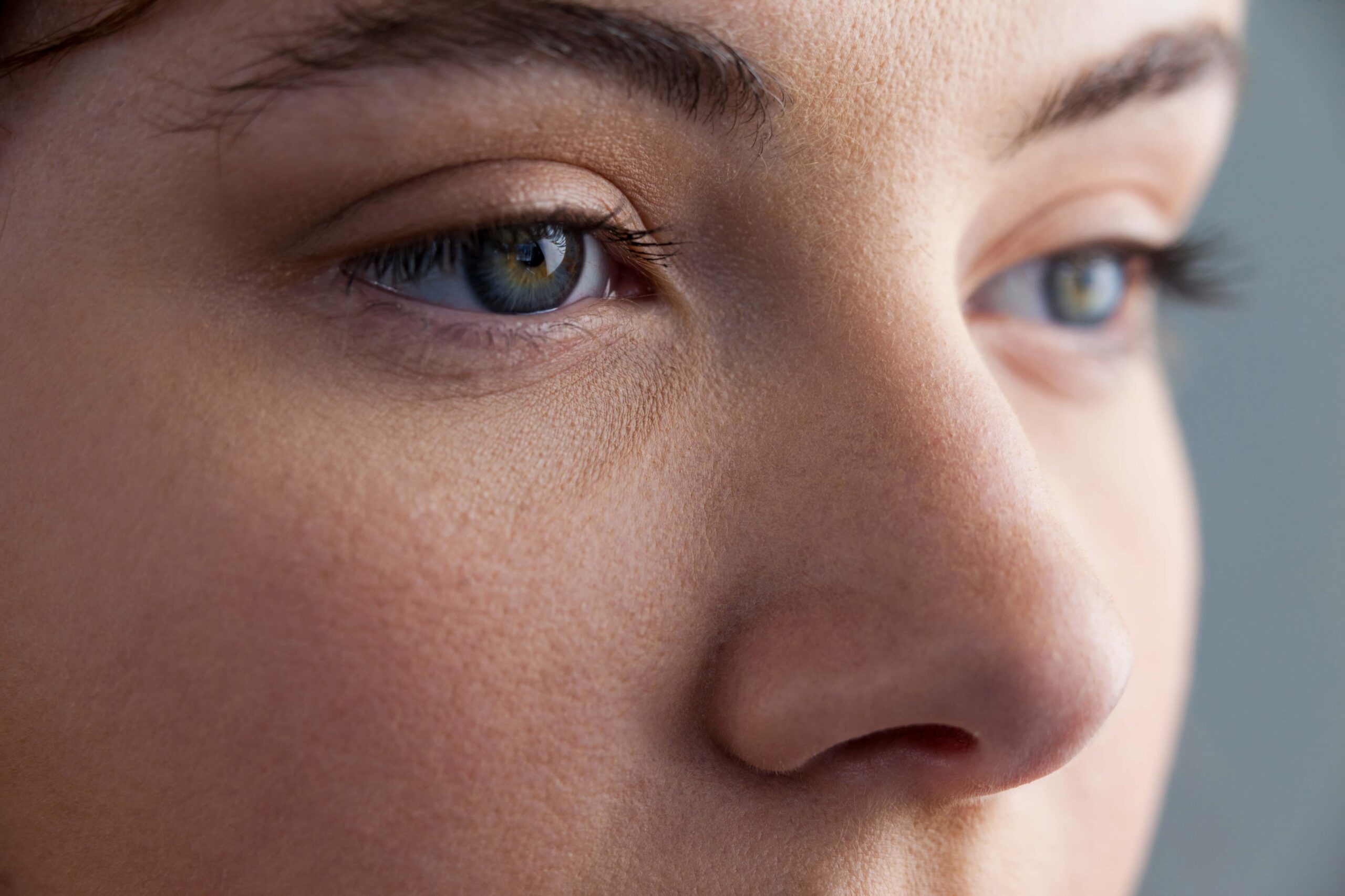 Close-up of a person's face, focusing on the nose and eyes. The skin appears smooth, and the eyes are blue with noticeable eyelashes. The image is well-lit, highlighting facial features.
