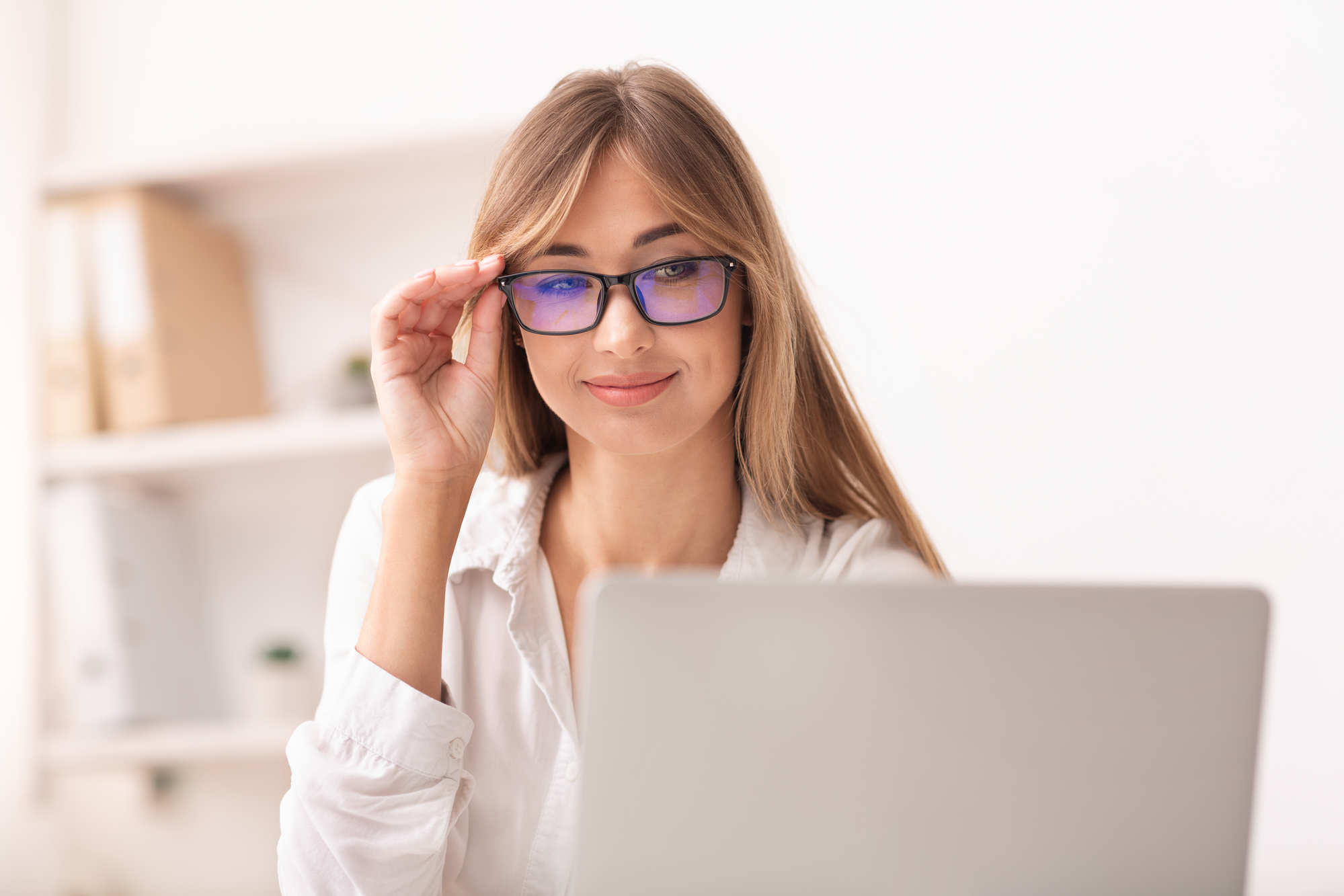 Woman in eyewear using laptop working in office